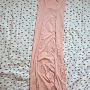 Ljusrosa långklänning - Säljer en elegant ljusrosa långklänning. Klänningen har en offshoulder-design som ger en stilren look. Perfekt för speciella tillfällen när du vill känna dig extra fin.