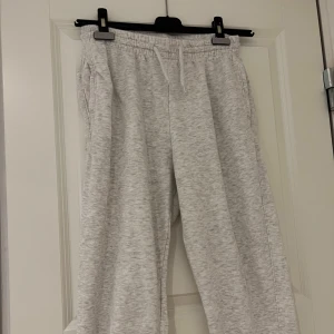 Grå mjukisbyxor från H&M - Säljer ett par grå mjukisbyxor från H&M. De har en elastisk midja och muddar vid bensluten för en bekväm passform. Perfekta för en avslappnad stil.