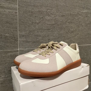 Beige och vita sneakers från Mason Margiela - Snygga sneakers i beige och vitt med bruna sulor. Lite defekt på boxen men skorna är i stort sett bara använda någon enstaka gång inomhus!      Pris kan diskuteras vid smidig affär! Tyvärr inget kvitto det har försvunnit med tiden.