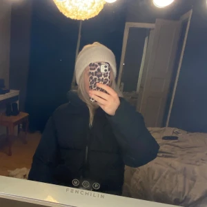 Svart pufferjacka - Säljer en svart pufferjacka med dragkedja. Jackan har en hög krage och långa ärmar, perfekt för kyliga dagar. Den är både stilren och bekväm, idealisk för vintern.