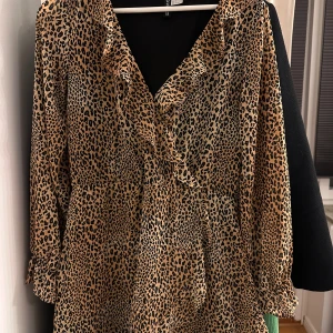 Leopardmönstrad klänning - Trendig leopardmönstrad klänning med volangdetaljer och v-ringning 