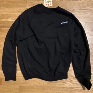 Svart sweatshirt från Corteiz - Säljer en svart sweatshirt från Corteiz med deras logga broderad på bröstet. Tröjan har långa ärmar och en klassisk rund halsringning. Perfekt för en avslappnad stil. Storleken är S-M och Jag har 3 kläder till från samma märke som passar den här budet kan börja från 600kr efter som många kommer att vilja ha den. Försök att köpa alla kläder samtidigt om du kan eftersom då blir leveransen smidigare