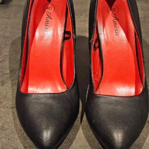 Svarta pumps från Amise - Snygga svarta pumps från Amisu med röd insida. De har en elegant spetsig tå och hög klack, perfekt för en stilren look.