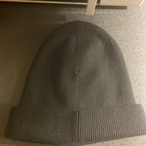 Svart mössa från Sail Racing - Snygg svart mössa från Sail Racing med uppvikt kant och logotyp framtill. Tillverkad i en blandning av ull och akryl för extra värme och komfort. Perfekt för kyliga dagar.