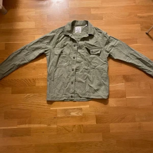 Grön overshirt från Only & Sons - Säljer en grön overshirt från only & sons med knappar framtill och två bröstfickor med lock. Perfekt för lager-på-lager-stil och har en avslappnad passform. Passar bra till både jeans och chinos.