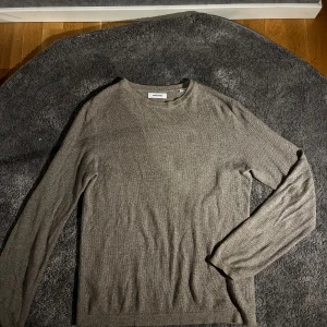 Grå jack & jones tröja - Säljer en stilren grå långärmad tröja från jack & jones. Bra skick och den är ganska luftig så den är bra när det blörjar bli lite varmare. Hör av er vid funderingar 