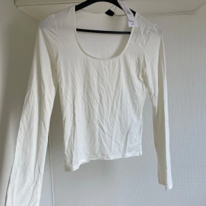 Vit långärmad topp från Gina Tricot - Säljer en vit långärmad topp från Gina Tricot i mjukt jerseytyg. Toppen har en rund halsringning och är perfekt för en stilren look. Passar bra till både jeans och kjol. 🌟