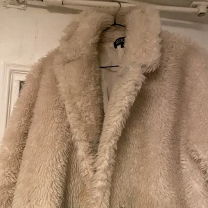 Beige teddyjacka från Bershka - Mysig beige teddyjacka från Bershka med fluffig textur och bred krage. Perfekt för kyliga dagar när du vill hålla dig varm och stilren. Jackan har en avslappnad passform och är ett måste i garderoben för den som älskar komfort och mode.