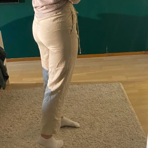 Beige byxor med snörning - Snygga beige byxor från H&M med elastisk midja och snörning framtill. Byxorna har en rak passform och är tillverkade i ett mjukt material. Skulle säga att de är petite då de är lite korta på mig som är 160 cm.