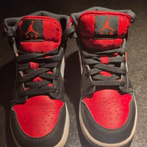 Nike Air Jordans i rött och svart - Snygga Nike Air Jordans i klassisk röd och svart färgkombination. Skorna har en ikonisk design med snörning och den välkända Jumpman-loggan på plösen. Perfekta för sneaker-entusiaster!