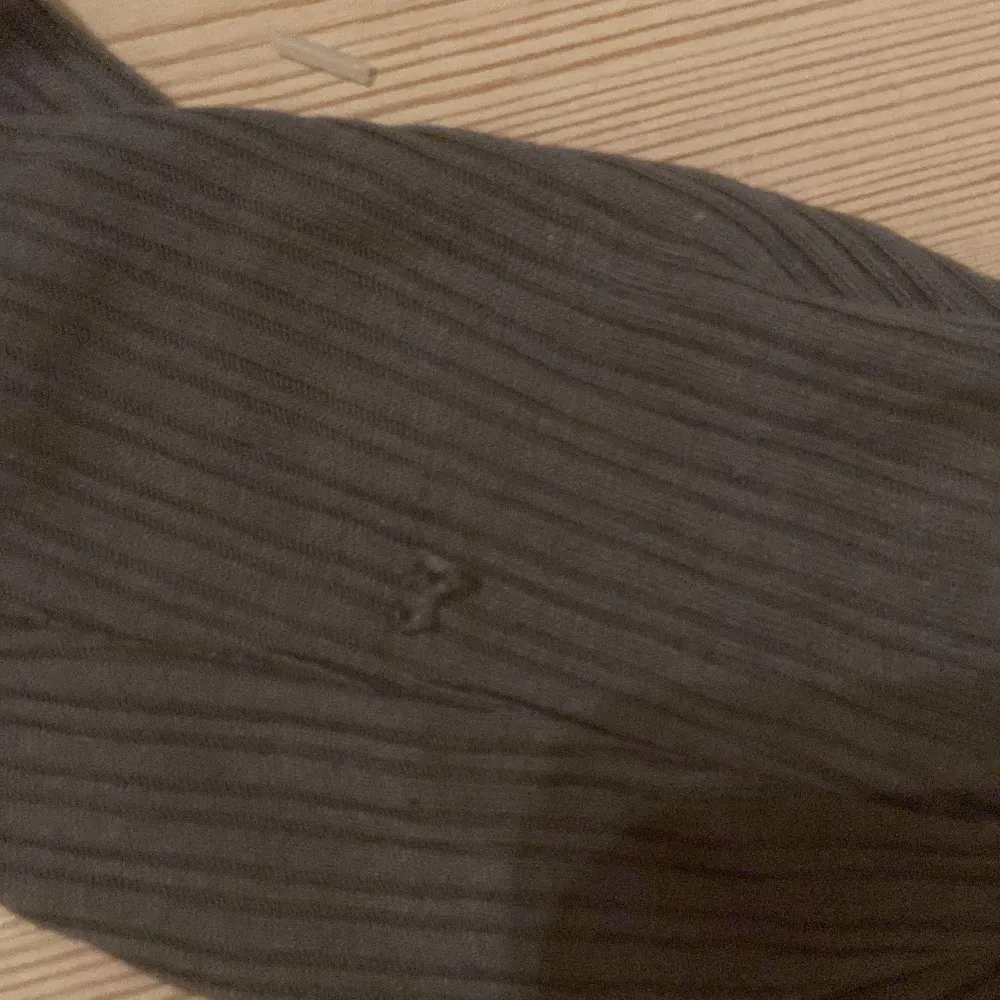 Säljer en stilren grå ribbad topp med långärmad design. Toppen har en söt rosett och spetsdetaljer vid halsringningen. Perfekt för en avslappnad look.. Neuletakit & Villapaidat.