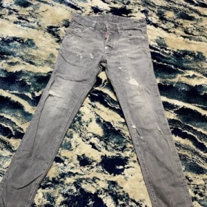Grå jeans Dsquared2 - Snygga grå jeans från Dsquared2 med slitna detaljer och en straight passform. De har en klassisk femficksdesign och knappgylf. Perfekta för en avslappnad stil.