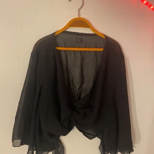 Svart bolerotopp från Shein - Elegant svart bolerotopp från Shein med knytning framtill. Den har en luftig design med trekvartsärmar och en lätt transparent look. Perfekt för att lägga till en stilfull touch till din outfit.