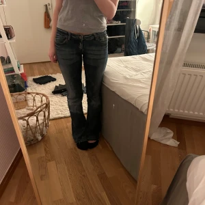 Mörkblå jeans med bootcut - Snygga jeans men en cool dragkedja som detalj! Har inga mått men de är väldigt stretchiga i materialet så skulle säga att storleken är 36/38