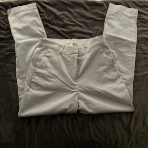 Ljusblå kostymbyxor från H&M - Snygga ljusblå kostymbyxor från H&M med en klassisk design. Byxorna har en rak passform och stängs med en dragkedja och hyska. Perfekta för en stilren look.