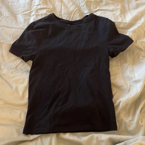 Svart t-shirt från H&M Divided - Säljer en klassisk svart t-shirt från H&M Divided. Den har en enkel design med korta ärmar och rund halsringning. Perfekt basplagg för alla tillfällen.