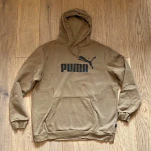 Beige hoodie från Puma - Säljer en snygg beige hoodie från Puma med deras ikoniska logga tryckt på framsidan. Tröjan har en klassisk känguruficka och en bekväm huva. Perfekt för en avslappnad stil. köptes för 340kr säljs för 240kr