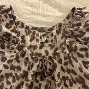 Leopardmönstrad blus  - En leopardmönstrad blus med knytbar rosett framtill. Köpt här på Plick men aldrig använd.
