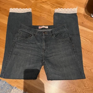 Levi's jeans med spetsdetaljer - Snygga Levi's 505 jeans i mörkblå denim med unika spetsdetaljer vid benslut och bakfickor som jag har sytt på själv. Modellen är straight och mid/lowwaist.  Säljer då jag aldrig använder dem längre🫶🏻midjelängd:40 cm. Innerbenslängd:76 cm