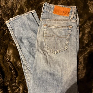 Ljusblå jeans från Tiger Of Sweden - Snygga ljusblå jeans från Tiger Of Sweden med klassisk femficksdesign och knappgylf. Jeansen har en stilren look med en läderpatch baktill. Perfekta för en avslappnad stil.