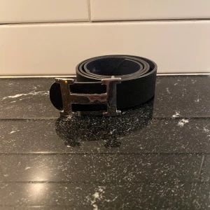 H bälte  - Säljer nu detta bälte med en silvrig H ikon och svart läder. Använt och finns defekter men inget som påverkar användning. Hör av er vid frågor