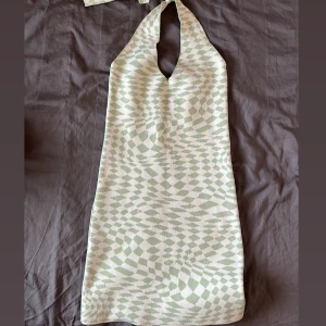 Mönstrad halterneckklänning - Trendig halterneckklänning med ett unikt geometriskt mönster i ljusgrönt och vitt. 