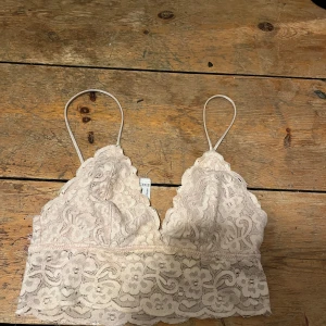 Beige spetslinne från Forever 21 - Säljer ett vackert beige spetslinne från Forever 21. Linnet har tunna axelband och ett fint blommigt mönster. Perfekt för en somrig look eller som ett lager under andra plagg.