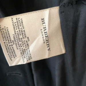 Zip up hoodie Burberry  - Snygg svart jacka från Burberry med huva i klassiskt rutmönster. Jackan har dragkedja framtill och en ficka med dragkedja på bröstet. Perfekt för höst och vår.