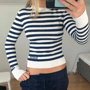 Randig långärmad tröja från Guess - Säljer en snygg randig tröja från Guess i blått och vitt. Tröjan har långa ärmar och en tight passform, perfekt för en stilren look. Den är tillverkad i ett mjukt material som känns skönt mot huden.