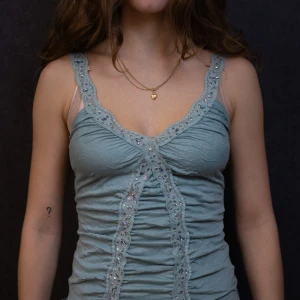 Turkos fest-topp med glittriga spetsdetaljer - Snygg turkos fest-topp med spetsdetaljer och glittrande paljetter framtill. Toppen har en åtsittande passform och är i ett bekvämt mjukt material.