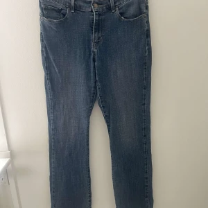 Blå jeans från Levi's - Snygga blå jeans från Levi's med klassisk femficksdesign och knappgylf. De har en rak passform och är perfekta för en avslappnad stil. Levi's-loggan syns tydligt på bakfickan och etiketten i midjan.