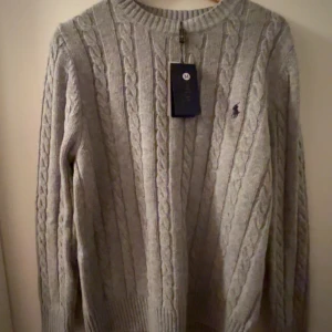 Grå stickad  Ralph Lauren - Säljer en stilren grå stickad tröja från Ralph Lauren. Den är i nyskick kvittot saknas tyvärr kom med ett bud !