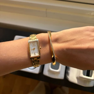 Kate Spade Armband - Stelt armband eller bangle från Kate Spade i guldpläterat rostfrittstål. Framsidan är ”tvistad” med stenar och baksidan är blank. Har någon repa (se bilder) men är generellt väldigt bra skick. 