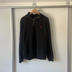 Svart tröja med dragkedja från Ralph Lauren - Säljer en stilren svart tröja från Ralph Lauren med dragkedja och röd logga på bröstet. Tröjan är i medium men passar även mig som har small. Kan gå ned i pris vid snabba affär!