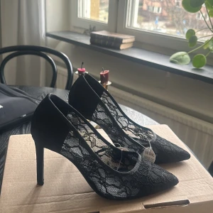 Svarta spetsiga pumps med spetsdetaljer - Eleganta svarta pumps med spetsig tå och klack. Skorna har vackra spetsdetaljer som ger en sofistikerad look. Perfekta för en stilfull kväll.