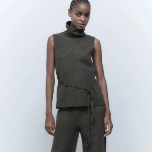 Mörkgrå ärmlös polotopp - Snygg mörkgrå ärmlös polotopp med knytband i midjan. Slutsåld från Zara! Har lite trådar från bandet men inget man märker av 