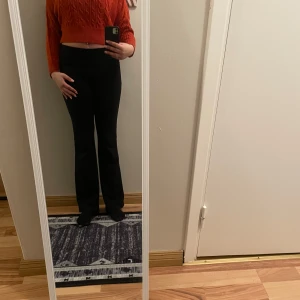 Orange stickad croppad tröja - Säljer en snygg orange stickad tröja med kabelstickat mönster. Tröjan är croppad och har långa ärmar med en bred ribbad kant vid ärmslut och nederkant. Perfekt för en trendig look! Står ingen storlek men hade gissat på s/m