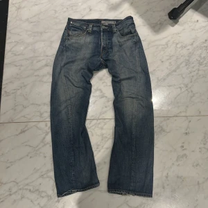 Vintage Levi’s twisted cut - Snygga blå Levi's Engineered Jeans med knappgylf och klassisk femficksdesign. Perfekta för en avslappnad stil med en vintage touch. Passar bra till sneakers eller kängor. Har en unik twistad design som är svår att se nu för tiden. Väldigt gammalt och historie rikt par. Pris kan diskuteras vid snabb affär. Har ett hål i vänster ficka