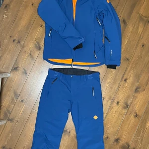 Skidställ från J.Lindeberg - Blå skidjacka från J.Lindeberg med matchande byxor. Som ny, använd en skidresa. 