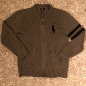 Grå Ralph Lauren zip - Säljer nu denna as snygga och eleganta grå zip med mörkblå detaljer från Ralph Lauren| Inga defekter, som ny och bara handtvättas!| Nypris runt 2 tusen kr| om man följer får man rabbat, vid frågor eller funderingar är det bara att höra av sig!🙌