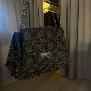 Svart axelväska  - Snygg svart axelväska med en unik textur och kedjehandtag