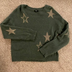 Mörkgrön stickad tröja med stjärnor från Rails - Säljer en mörkgrön stickad tröja från Rails med dekorativa stjärnor i en kontrasterande färg. Tröjan har långa ärmar och en bekväm passform, perfekt för kyligare dagar. Ett stilrent plagg som ger en unik touch till din garderob. Superfin med stjärnor och så himla skön!!