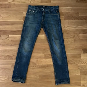 Blå jeans från Replay - Snygga blå jeans från Replay med klassisk femficksdesign och dragkedja. De har en straight passform och är perfekta för en avslappnad stil. Märkesdetaljer syns på bakfickorna och i midjan.