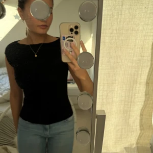 Svart ärmlös topp - Snygg svart ärmlös topp med draperad halslinje. Perfekt för en stilren look. Passar bra till både jeans och kjol.