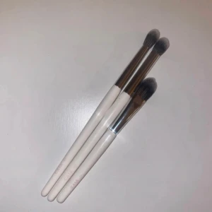  sminkborstar från CAIA - Säljer ett set med tre vita sminkborstar från CAIA. Borstarna har vita handtag och silverfärgade detaljer vid borsthuvudet. Perfekta för att applicera ögonskugga och concealer med precision.  OANVÄNDA! Finns några pytte små skav när dom legat mot något annat.  Nypris mellan 145-195 :- / styck 