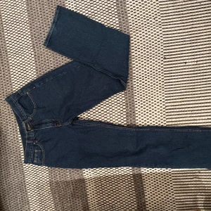 Mörkblå jeans från Chief - Snygga mörkblå jeans från Chief med klassisk femficksdesign och en läderpatch baktill. De har en rak passform och är perfekta för en avslappnad stil. Jeansen har en dragkedja och knapp framtill.