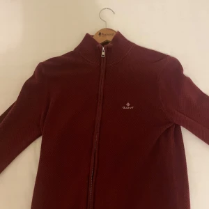 Röd tröja med dragkedja från Gant - Säljer en snygg röd tröja från Gant med dragkedja framtill. Tröjan har en hög krage och är perfekt för kyligare dagar. Den är stilren och passar bra till både jeans. Om ni har några frågor är det bara och skirva. Mvh Oskar