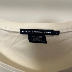 Vit t-shirt från Ralph Lauren - Säljer en stilren vit t-shirt från Ralph Lauren Sport med v-ringning och korta ärmar i storlek S. Den har en liten broderad logga på bröstet. Har fått gula fläckar, därav det billiga priset. Bara att skriva om fler bilder önskas💕