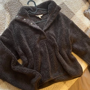 Brun fleece från H&M - Mysig brun teddytröja från H&M med en hög krage och knappar vid halsen. Tröjan har en avslappnad passform och är gjord i ett mjukt, fluffigt material.  Storlek S och i mycket gott skick!