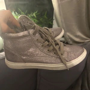 Glittriga sneakers i silver - Snygga glittriga sneakers i silver med snörning. Perfekta för att ge din outfit lite extra. Från Marco tozzi och är väl använda💕